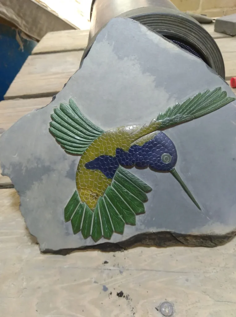 Stone Carvings of Humming Bird With Wings out Green Tips of Feathers, Blue Belly and Face, Yellow Back 