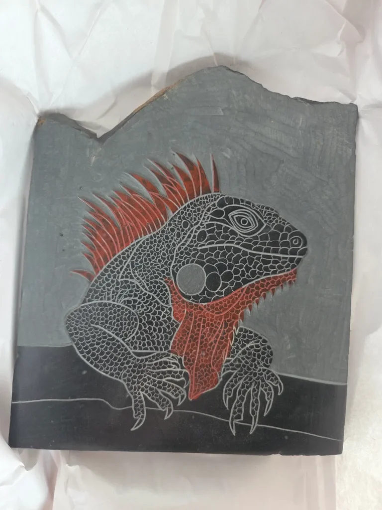 Stone Carvings of Lizard over an edge looking to the right withe Red Underbelly and Red Hair