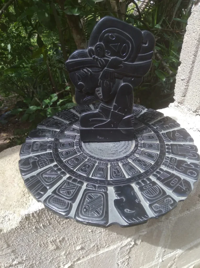 Stone Carvings of Mayan  Writing in a Black Circular Grid with a Second Piece Standing on Top of a Black Mayan Figure