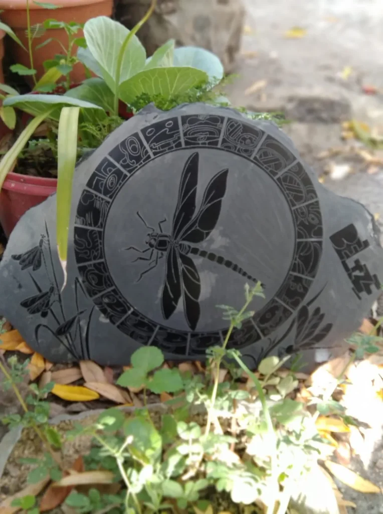 Stone Carvings of Mayan  Writing in a Black Circular Grid with a Black Dragonfly Center