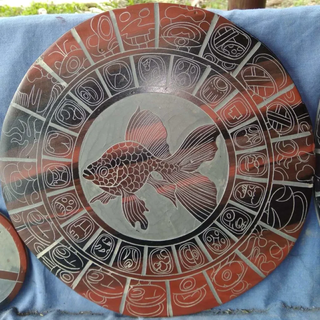 Stone Carvings of Mayan  Writing in a Red Circular Grid and Large Red Goldfish in Center